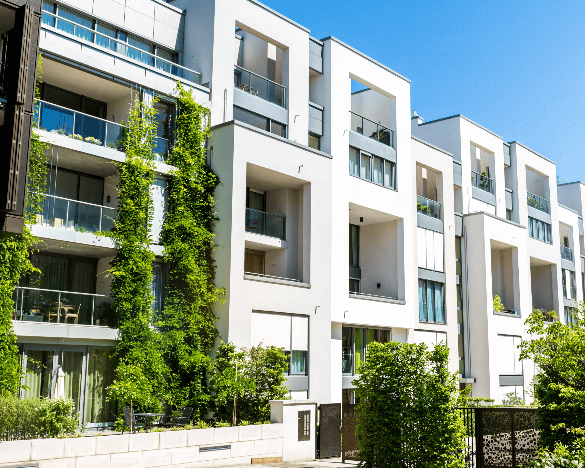 Contemporary multi-storey apartment building with glass balconies and vertical greenery