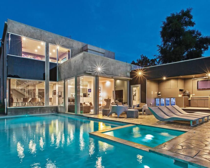 Home 1 Luxury modern home with illuminated swimming pool at dusk - Surveyoria Building Consultants
